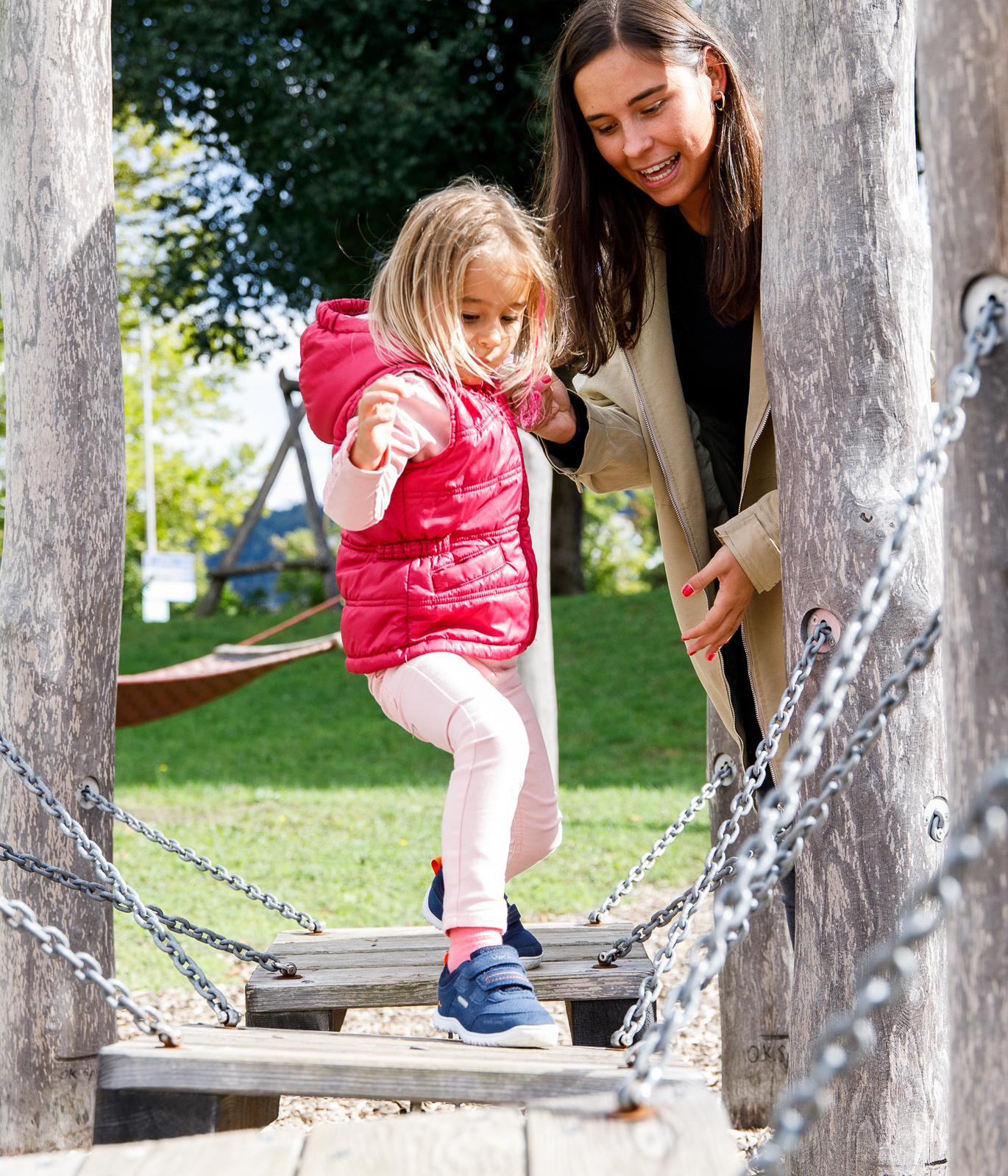Elementarpädagogin mit Kind auf Klettergerüst
